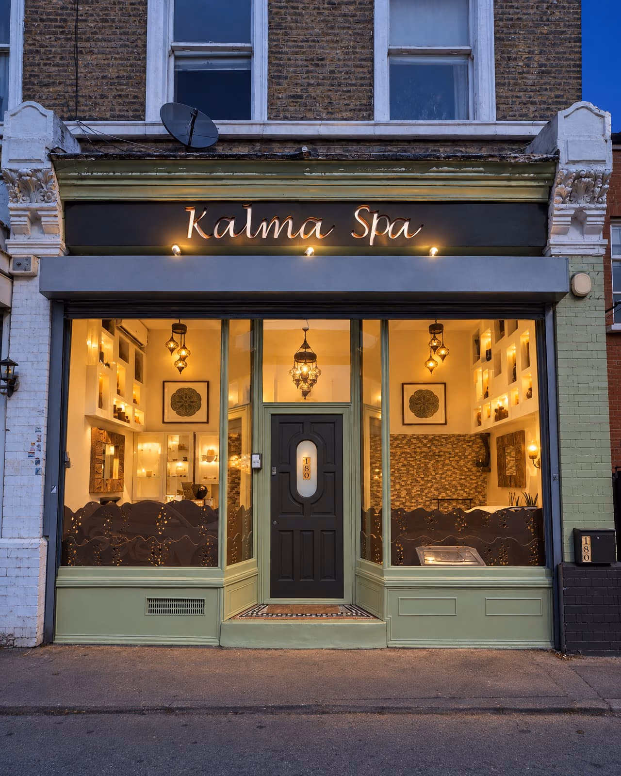 The Kalma Spa shopfront at dusk, the sign and the window lit.
